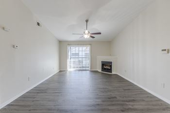 A spacious room with a fireplace and a ceiling fan.